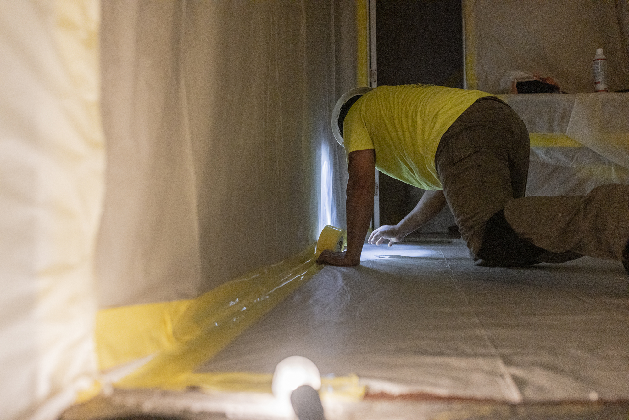 Worker sealing containment tape on the floor